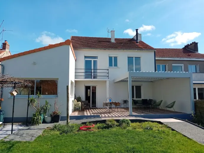 Maison rénovée avec façade blanche, menuiseries modernes et aménagements de terrasse.